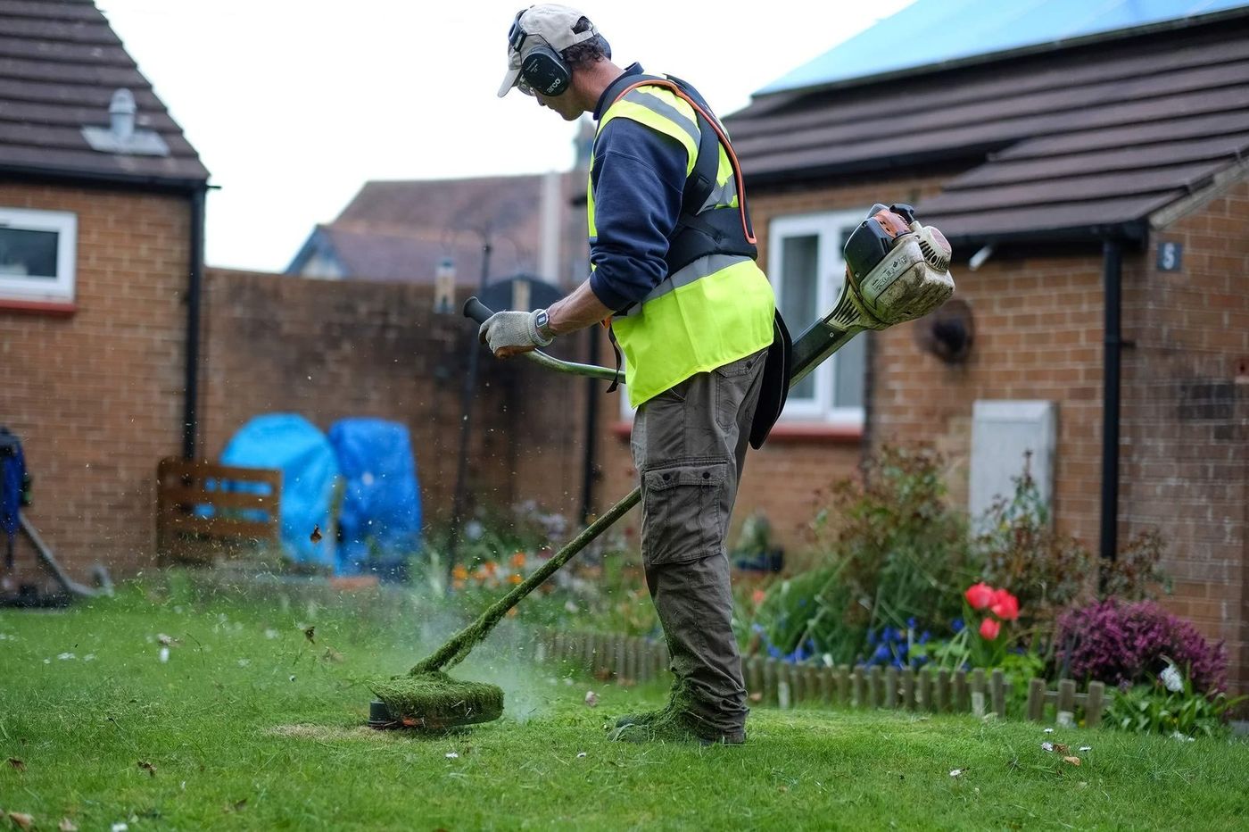 AdsFlair landscaping client strimming grass on a residential lawn maintenance job